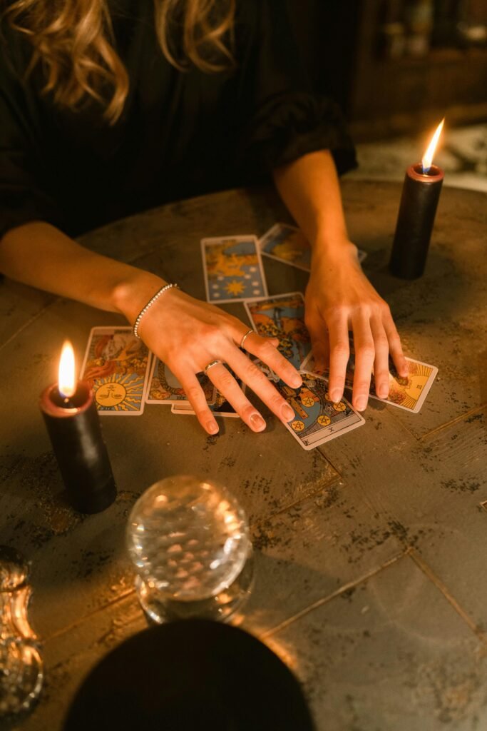 pexels-photo-6014339-6014339 A woman engaging in a tarot card reading with candles and a crystal ball on a dimly lit table.